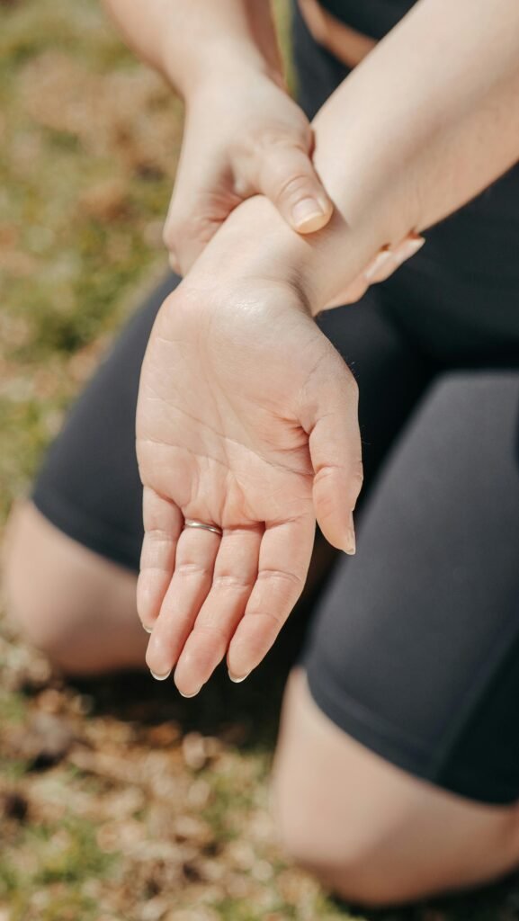 Close-up of a woman's hand holding her wrist outdoors, symbolizing injury or pain relief.